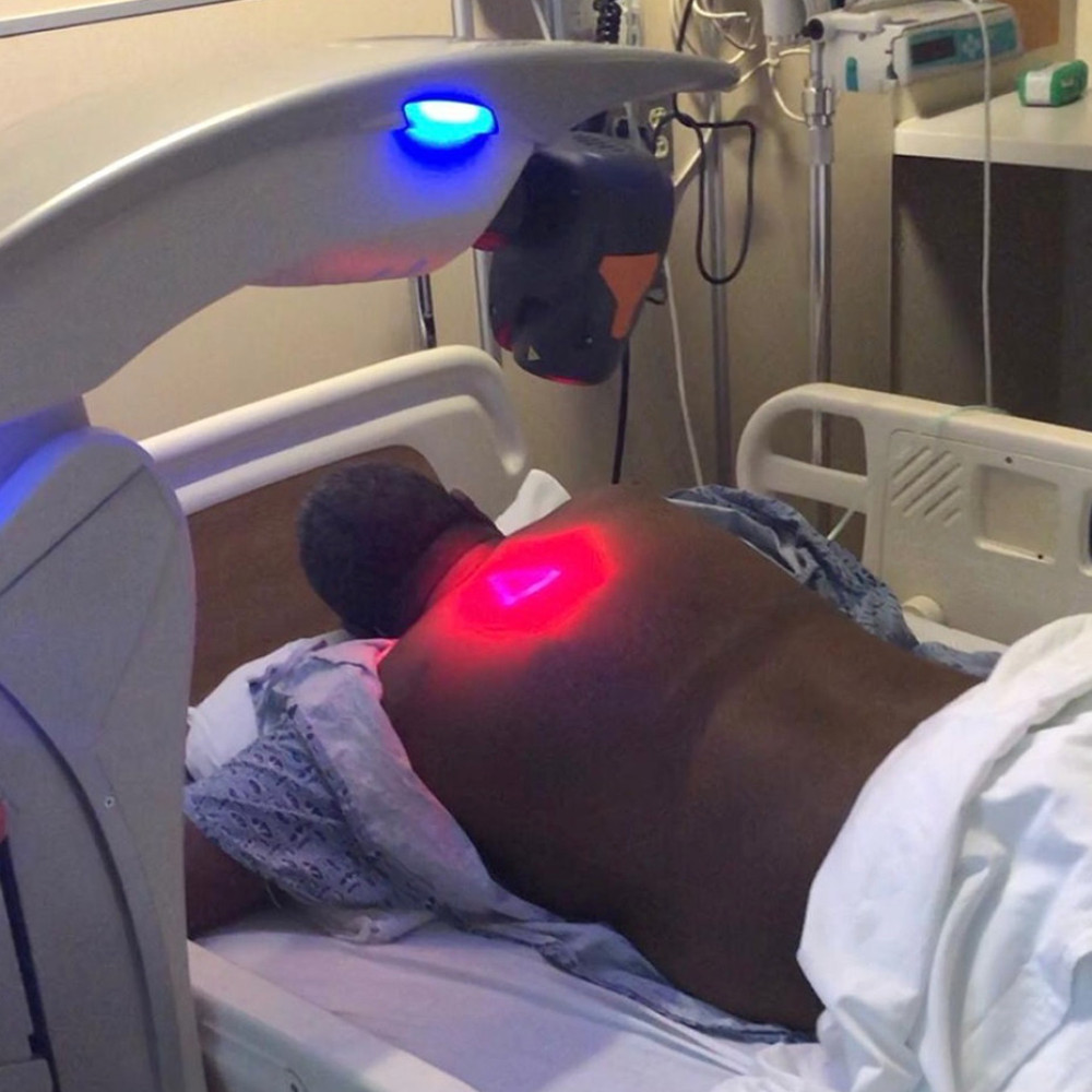 Laser scanner configuration while the patient is in the prone position with scapular protraction. The laser scanner was adjusted 20 cm above the skin as per manufacturer’s guidelines. The patient is shown here with his hands under his head for maximum scapular protraction. The red light is the laser machine’s guide beam on the skin. Infrared lasers with wavelengths of 808 and 905 nm are not visible to human eyes. The 2 sources are coupled in a single system in the MLS laser system.