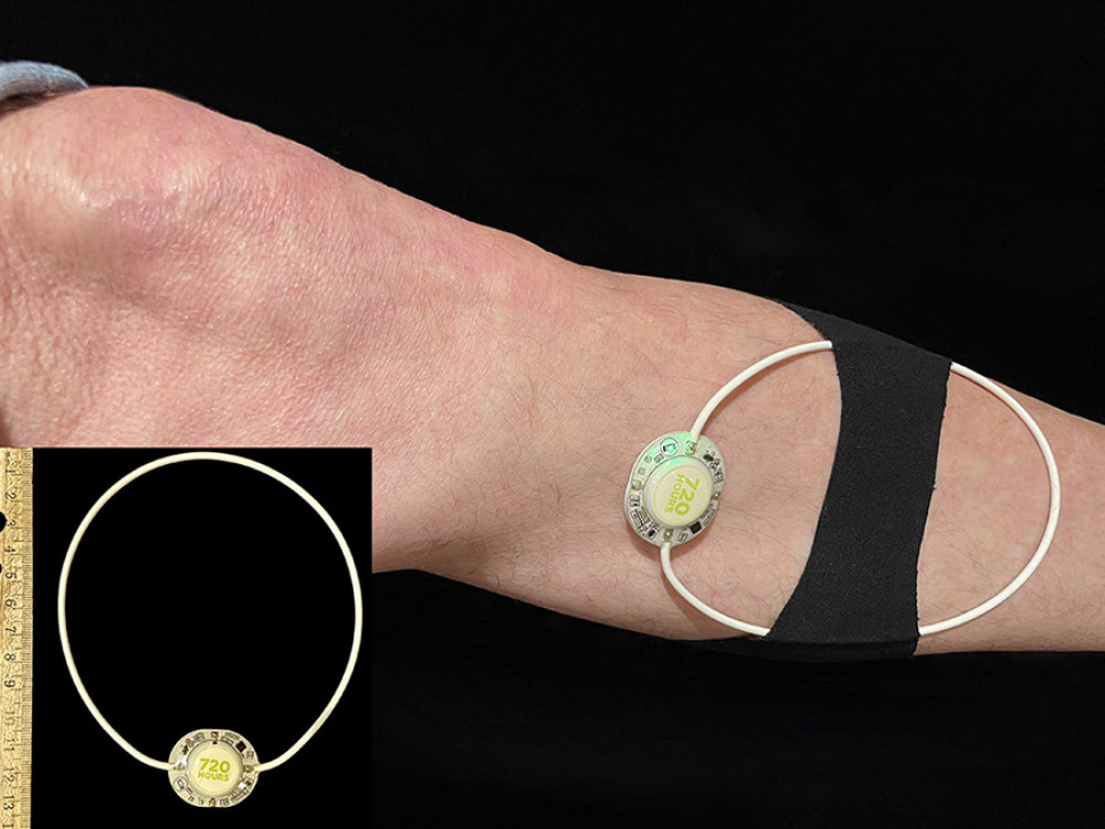 A wearable, pulsed shortwave device with a pulse generator and flexible 12-cm diameter antenna. The unit is secured with an included cotton-based kinesiology tape (black bandage in image). The single control is an on/off button on the back of the pulse generator, and the green light emitting diode indicates the unit is functioning.